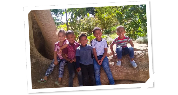 Kinder sitzen auf den Wurzeln eines Baumes