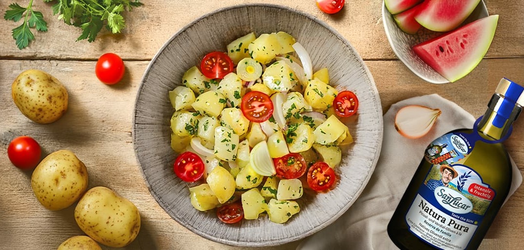 Potato salad with cherry tomatoes, onions, and herbs served with SanLucar Natura Pura olive oil
