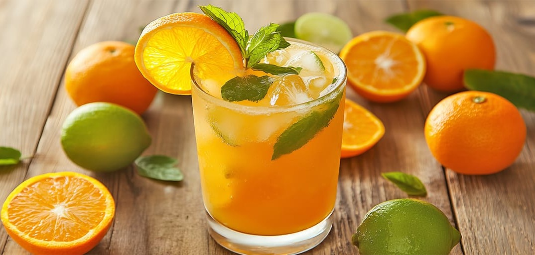 A glass of alcohol-free Mandarin Mojito garnished with fresh mint leaves and orange slices, surrounded by citrus fruits