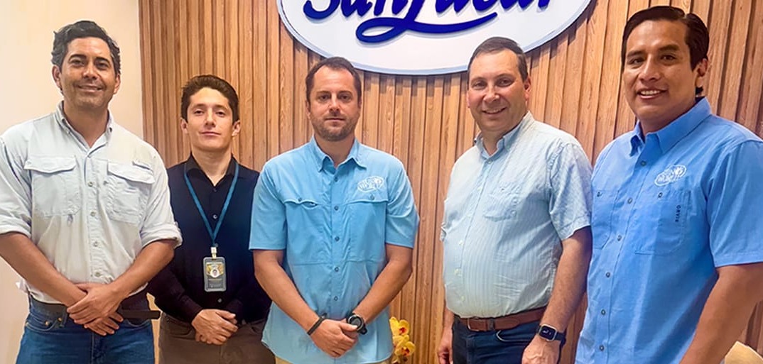 SanLucar team members standing together at company office in front of branded logo wall