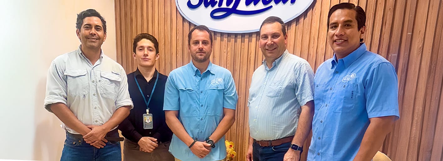 SanLucar team members standing together at company office in front of branded logo wall