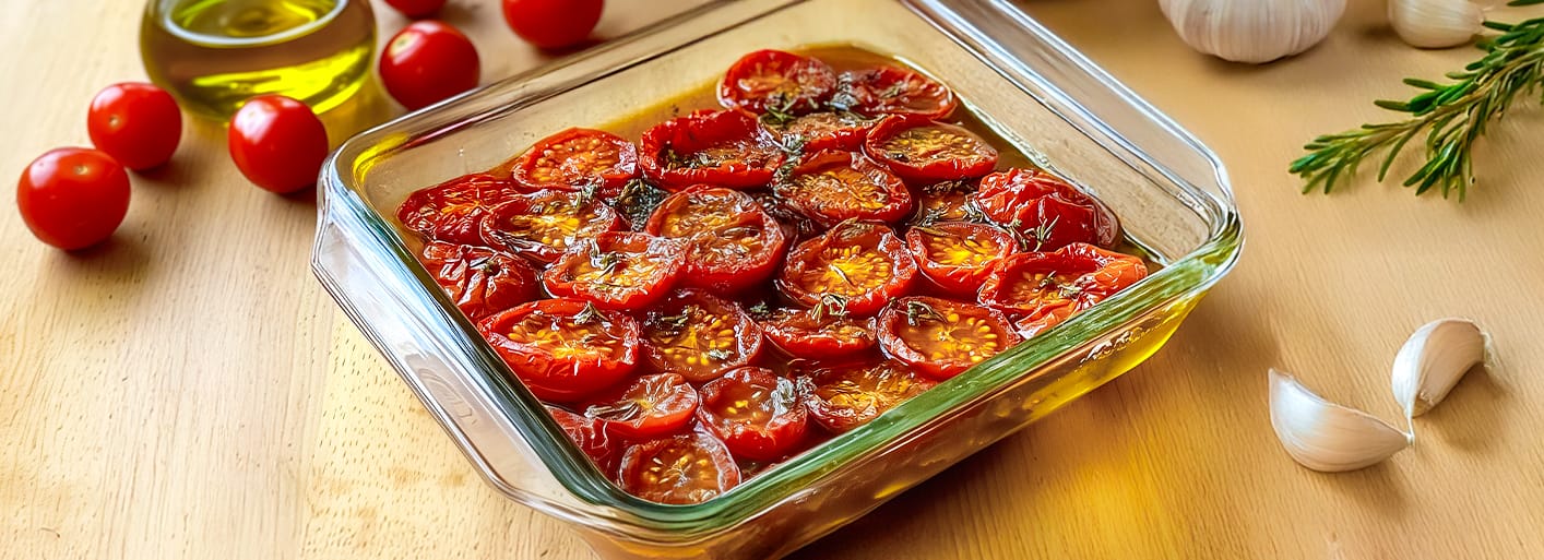 Homemade Sun-Dried Tomatoes_Header Baking dish with homemade sun-dried cherry tomatoes in olive oil with garlic and herbs